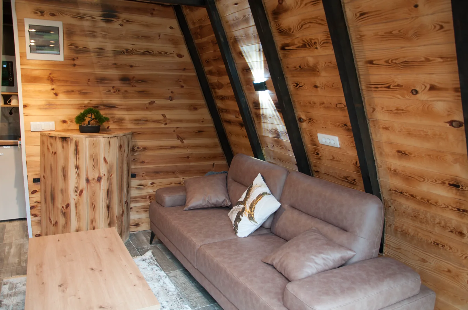 Dnevni boravak A-frame vikendice sa kožnom sofom i drvenim zidovima