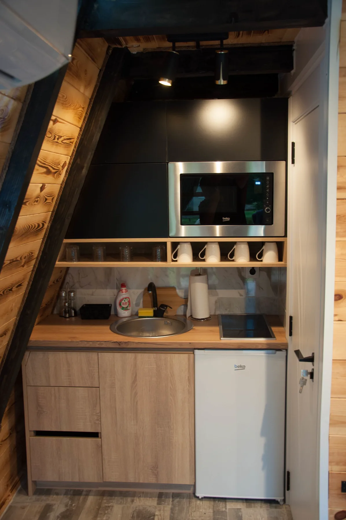 Opremljena kuhinja A-frame vikendice sa mikrotalasnom, sudoperom i frižiderom