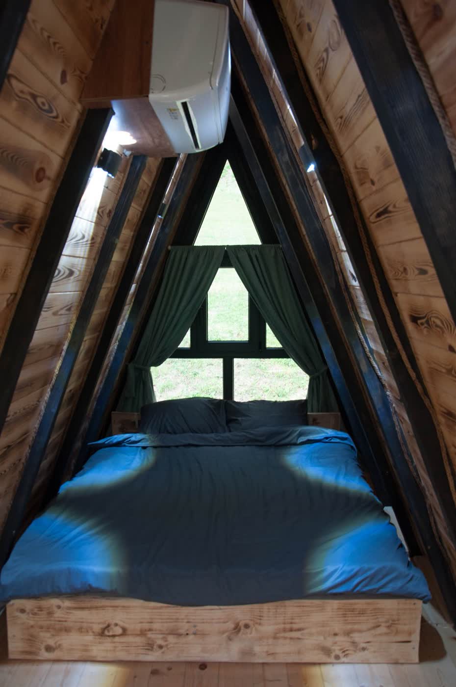 Krevet u potkrovlju A-frame vikendice s trouglastim prozorom